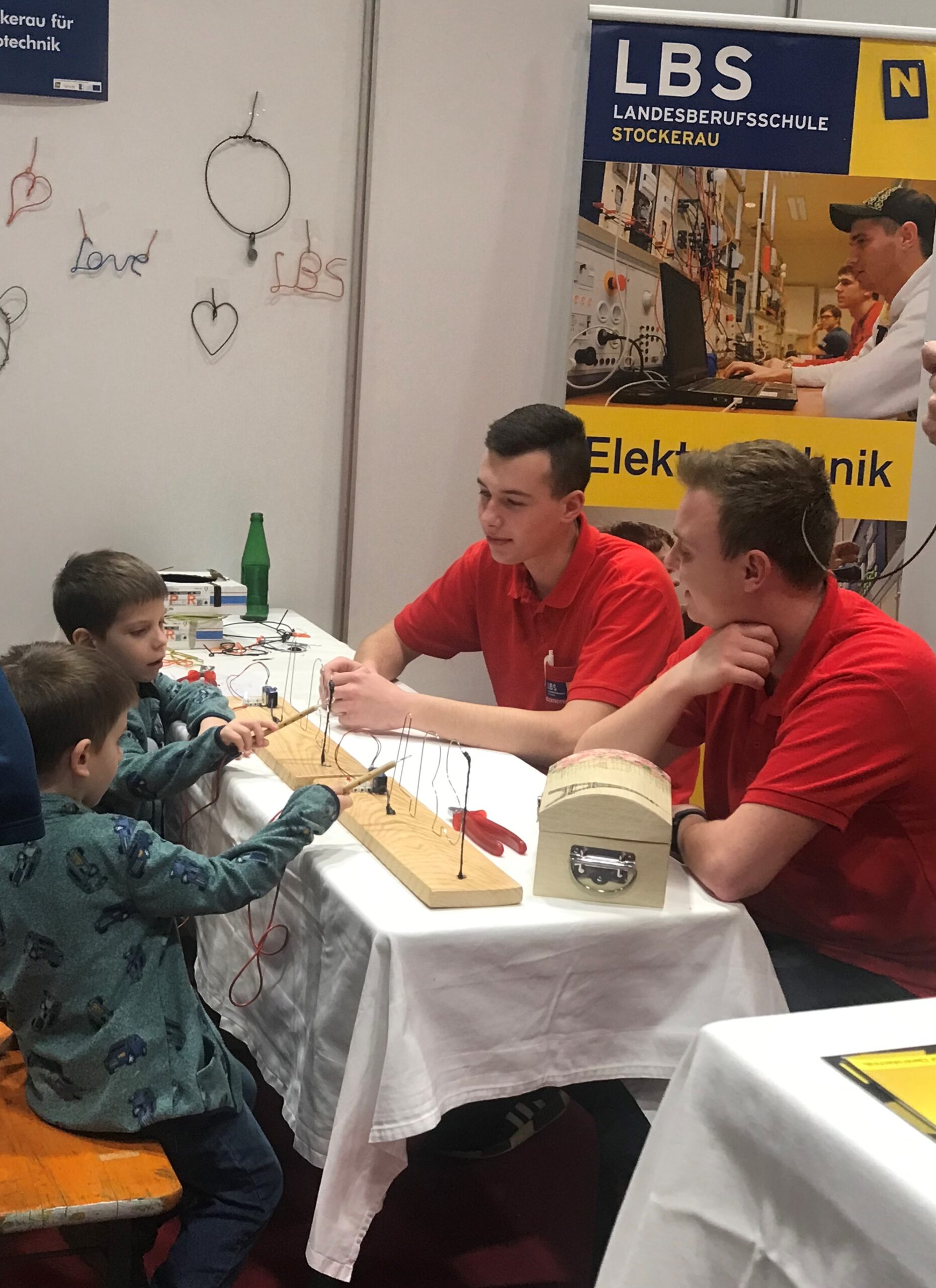 Messestand der LBS Stockerau mit zwei jungen Besuchern, die den "heißen Draht" begeistert ausprobieren